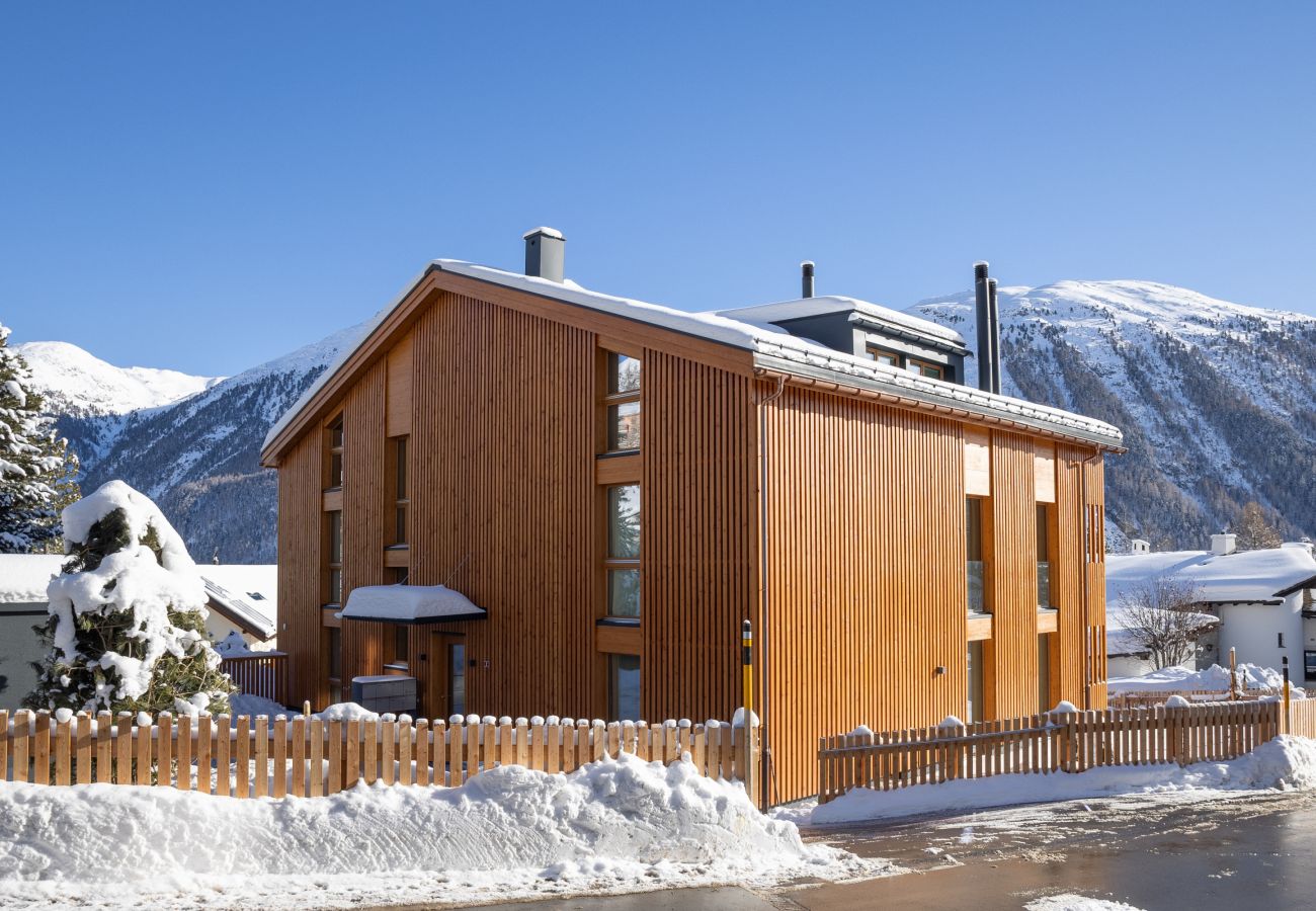 The wooden façade fits into the Engadine mountain landscape. In the background you can see Muottas Muragl